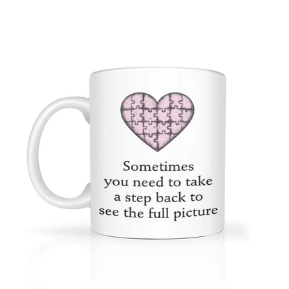 White mug with a pink heart puzzle design and text on a white background
