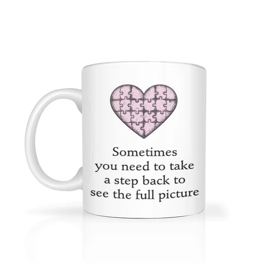 White mug with a pink heart puzzle design and text on a white background