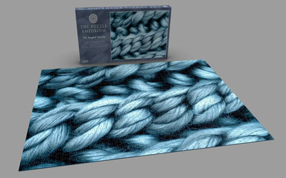 Jigsaw puzzle with blue yarn pattern and packaging on a gray background