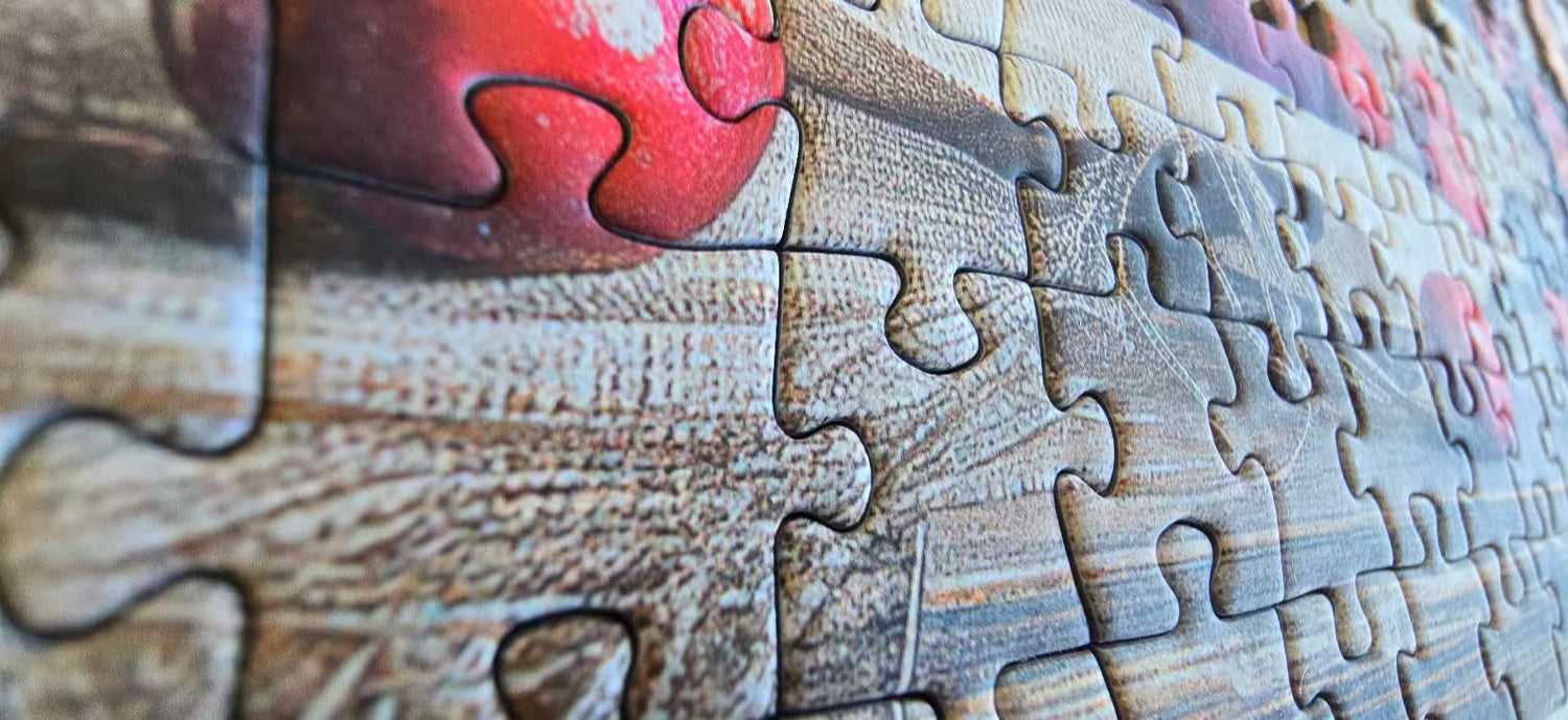 Close-up of a puzzle with wooden pieces, one piece shaped like a heart.