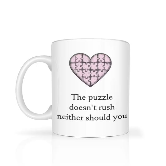 White mug with a pink heart-shaped puzzle piece design and text on a white background